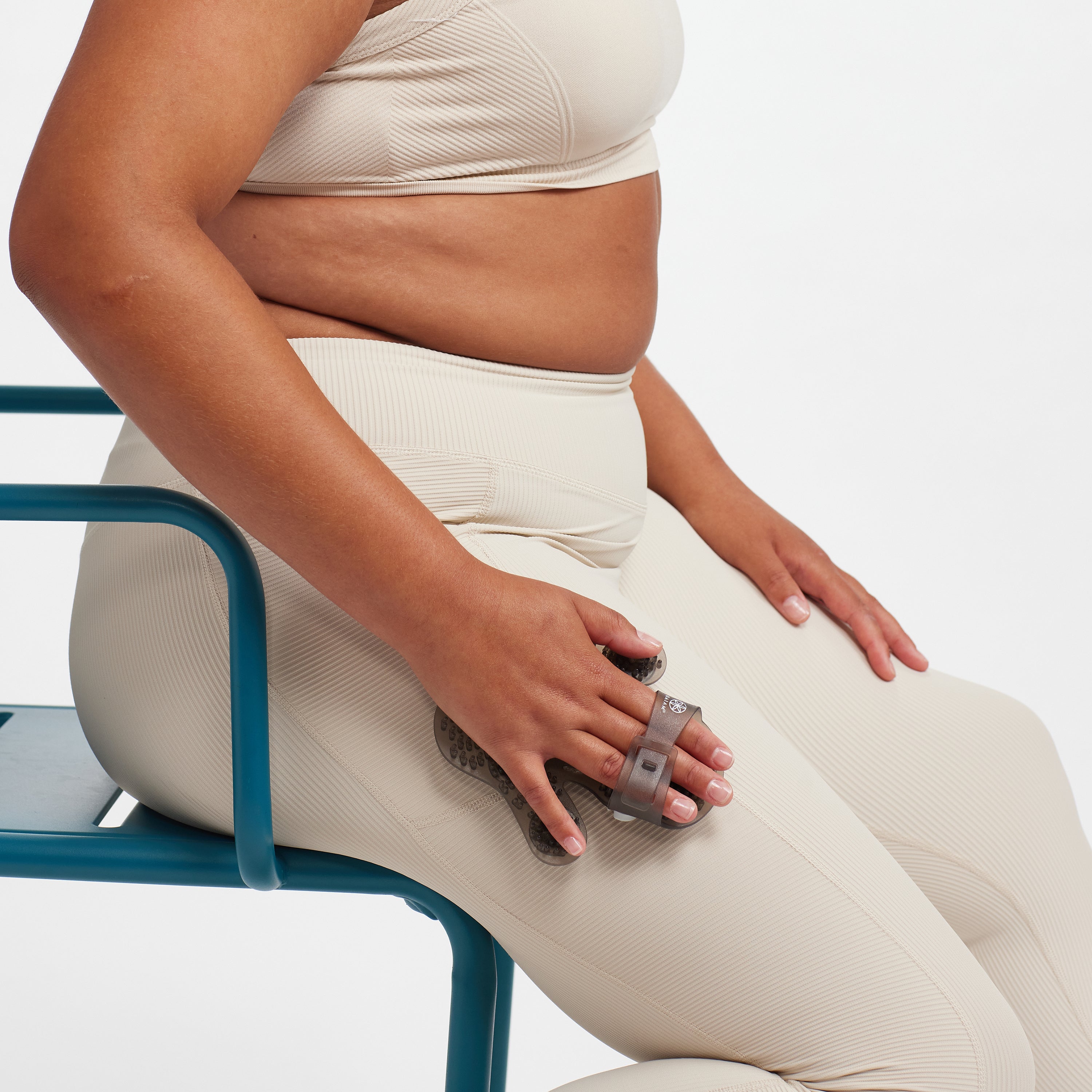 Person seated while using the Hand-Held Rolling Massager on the upper thigh